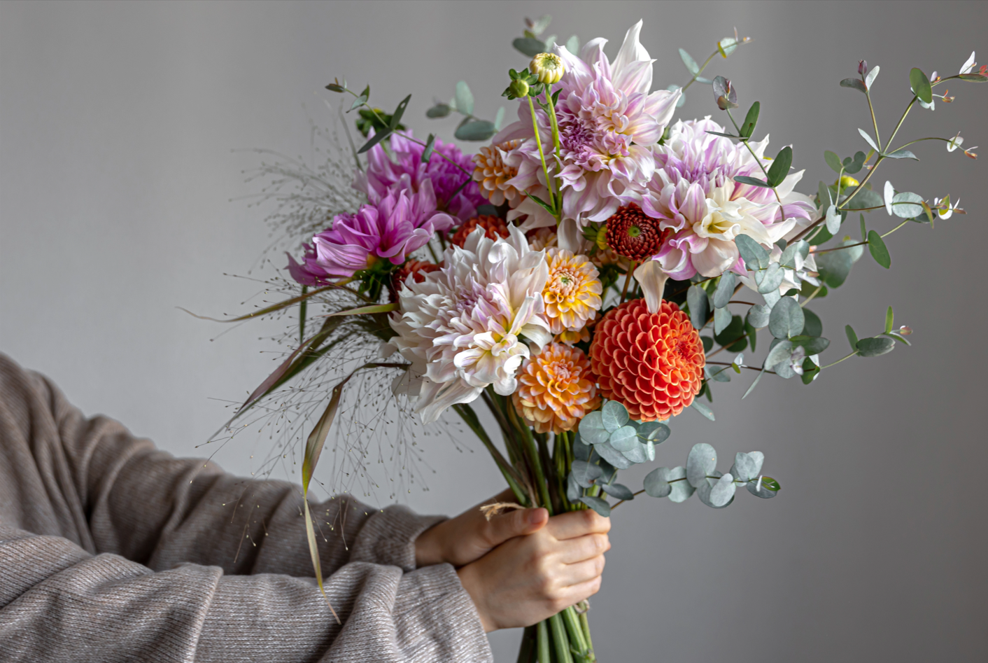 Frau mit Blumenstrauß inmitten blühender Blumen – Frische Blumen online kaufen und Freude schenken