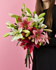 Hand haelt Lilienstrauss Rosa-Rot-Weiss